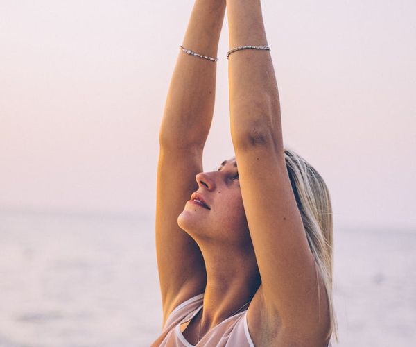Person meditating outdoors at sunrise with a look of serenity on their face.