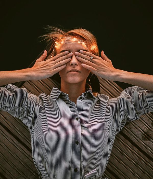 Woman in a peaceful yoga pose against a dark background with an orange glow.